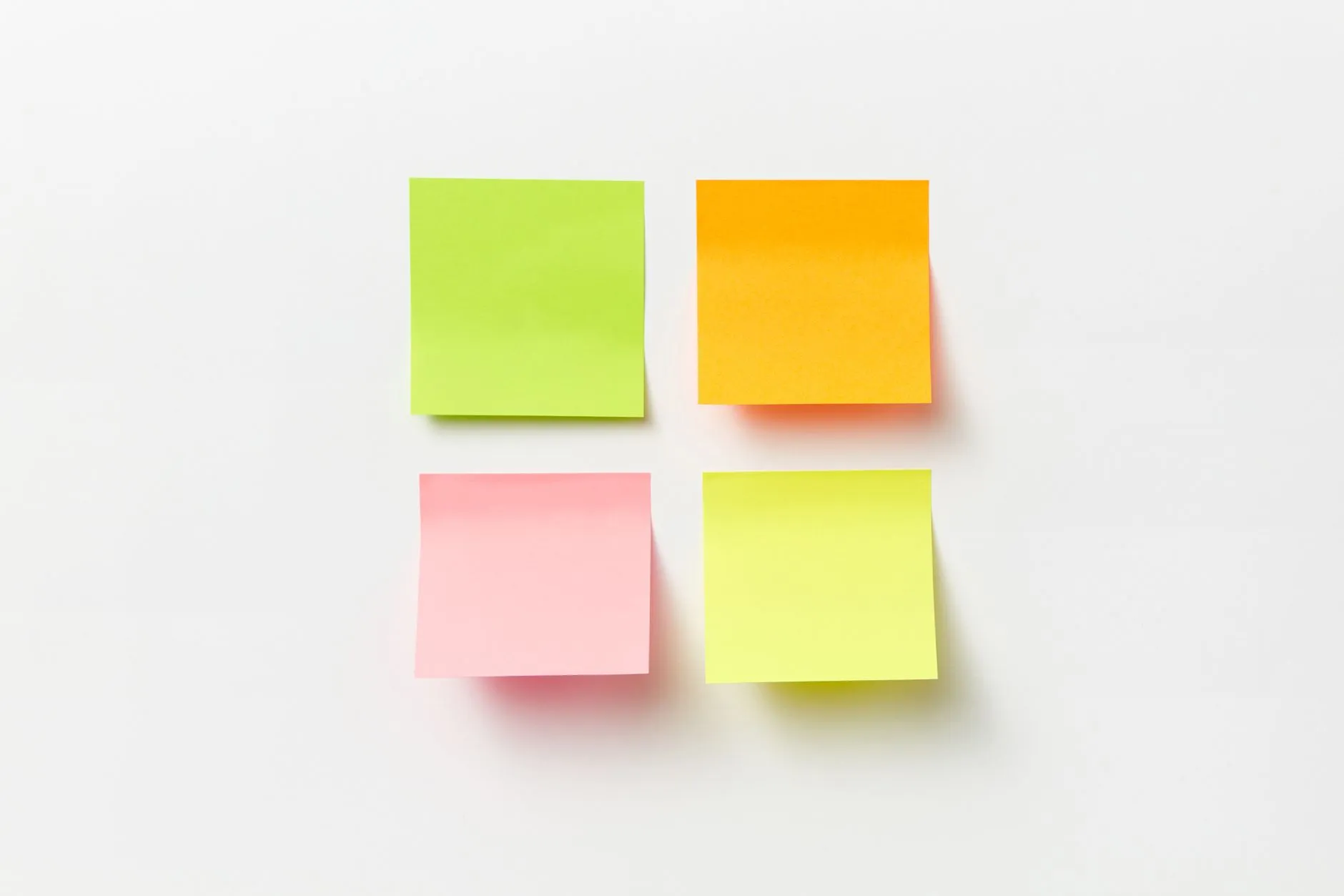 Four coloured sticky notes on a plain wall